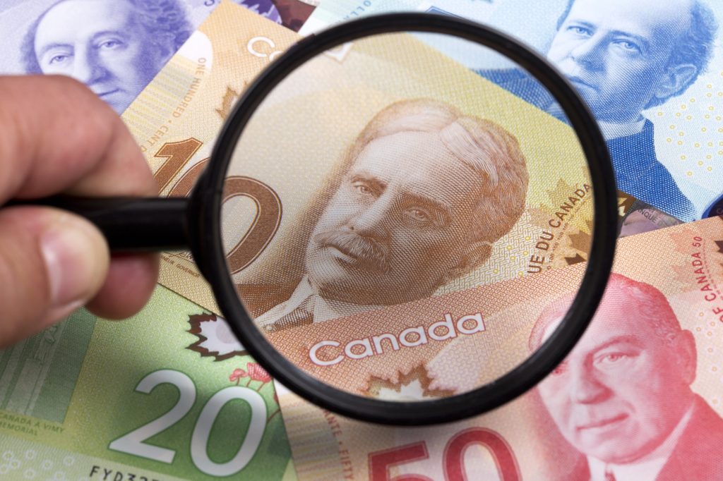 Canadian dollars in a magnifying glass